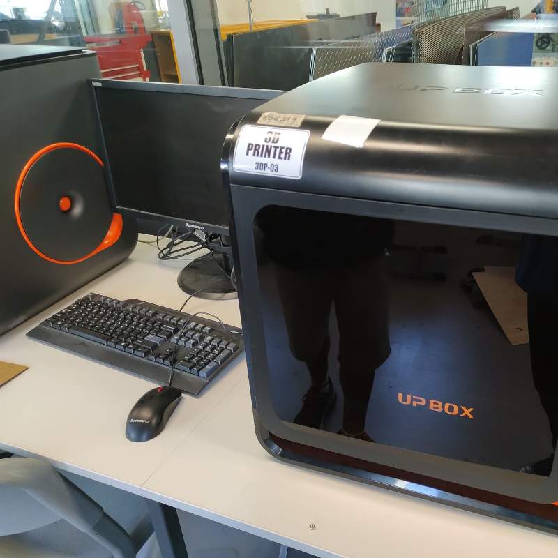 A computer is sitting on a desk next to a 3D printer.