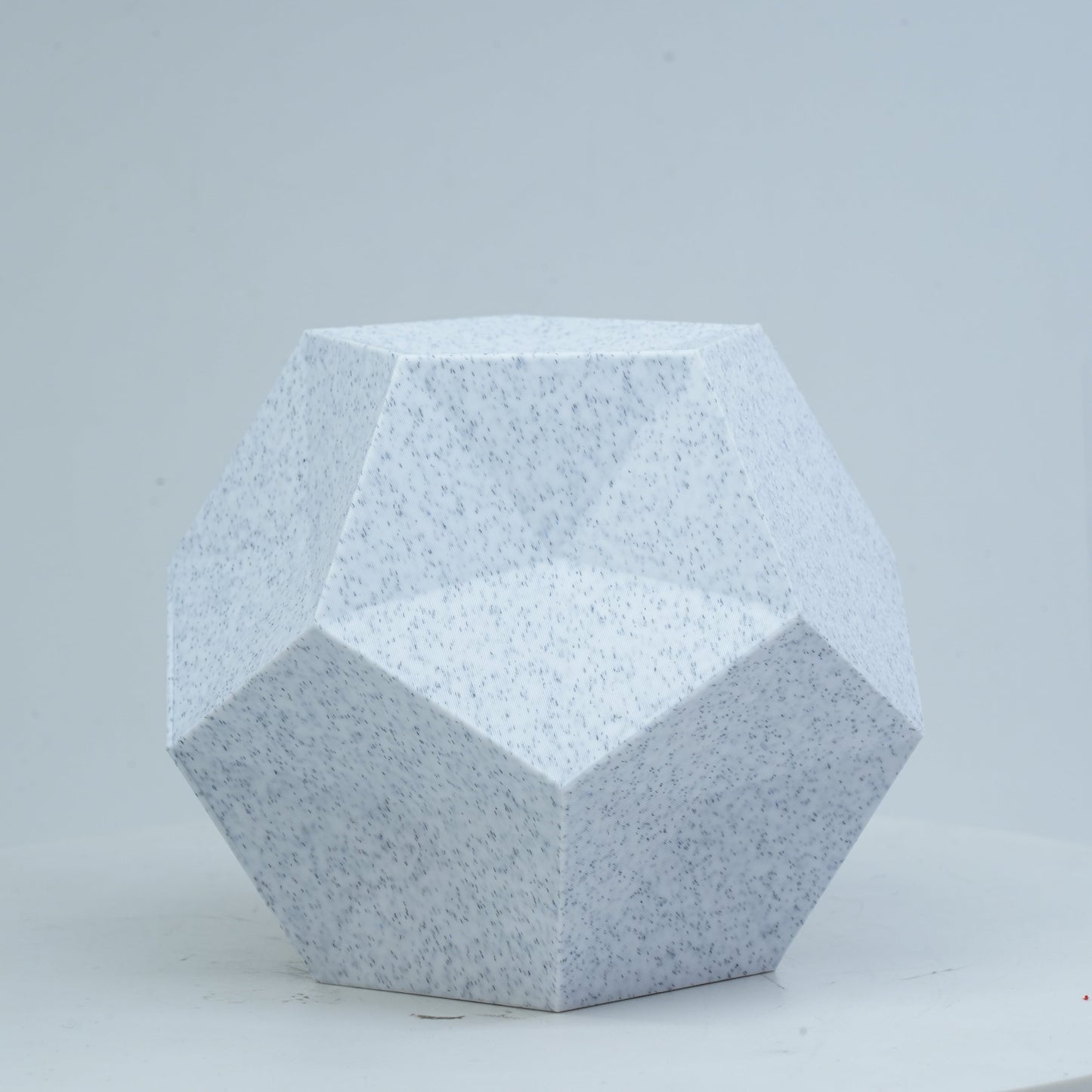 A dodecahedron printed with Flashforge PLA 1.75mm 3D Printing Filament in Marble Colour sits on a white round surface against a light background.