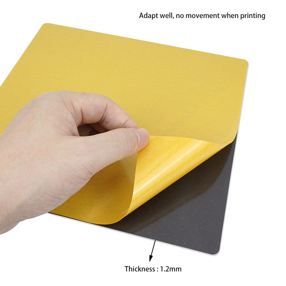A hand lifts a flexible 1.2mm thick yellow sheet from a black surface, demonstrating the excellent adhesion properties of the PEI PEO Dual-Sided 3D Printer Build Surface with Textured Base for Easy Print Removal by 3D Printing Perth - Cirrus Link. Text reads, "Adapt well, no movement when printing. Thickness: 1.2mm.