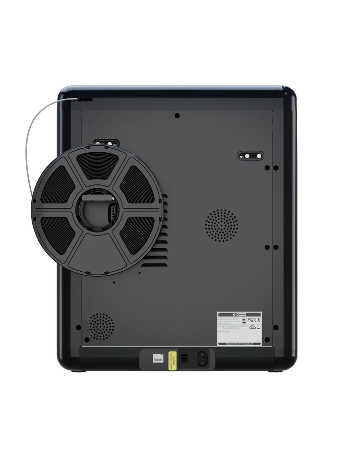 The image displays the back of the FlashForge Adventurer 5M Pro by FlashForge, featuring a circular spool, ventilation grills, and a power socket—engineered for quick setup and safe use in both home and school settings.