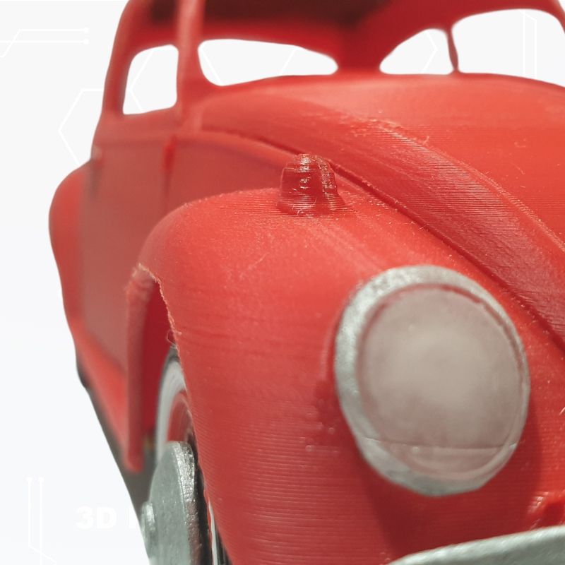 Close-up of a red toy car with detailed headlights and parts, showcasing its textured surface and design, reminiscent of the STL File : 1963 VW Beetle Vehicle by Gordon Nezich.
