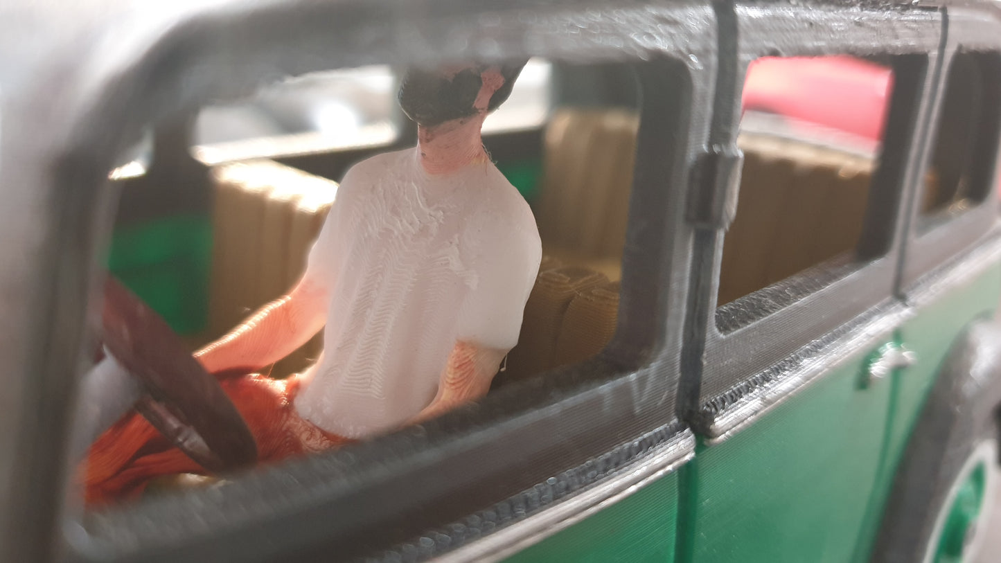 Close-up of a figurine seated in the driver's seat of a green toy car, partially obscured by the window; it looks like an exquisite 1930s Mercedes model STL File: 1930 Mercedes Vehicle by Gordon Nezich.