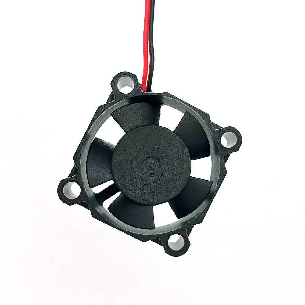 Against a plain white background, a compact black cooling fan featuring five blades and two red and black wires is displayed. The 24V 3010 DC Fan, measuring 30mm x 30mm x 10mm with a low noise level of 27.7 DBA and airflow of 4.2 CFM, from the brand '3D Printing Perth - Cirrus Link,' is ideal for ensuring optimal cooling in 3D printers.