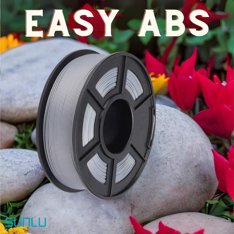A spool of SUNLU Easy ABS 1.75mm white 3D printing filament is labeled "EASY ABS" and sits on smooth stones with red flowers in the background.