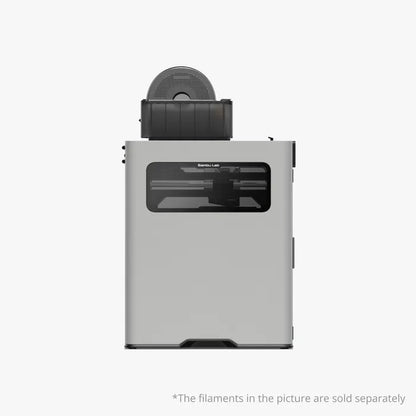 The Bambu Lab H2D 3D Printer by Bambu Lab is shown with a filament spool on top and a transparent front panel. Featuring dual-nozzle technology for versatile multi-material printing. Filaments sold separately.