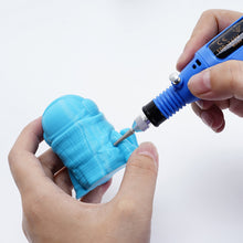 A DIY enthusiast expertly uses a blue Electric Sander Mini Electric Grinder Tool USB Adjustable Speed with Heads from 3D Printing Perth - Cirrus Link to engrave intricate details into a small blue 3D-printed figurine.