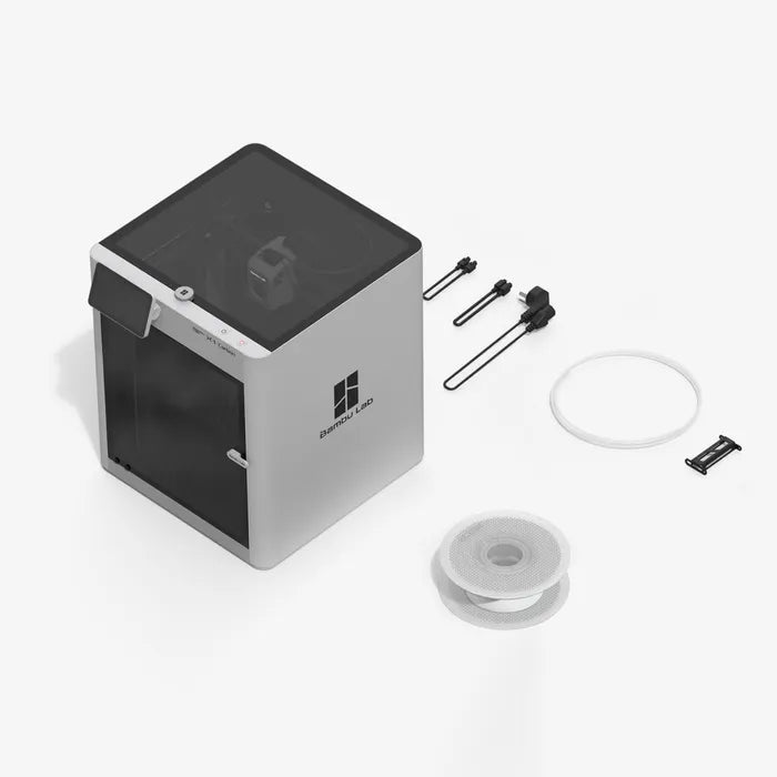The Bambu Lab X1C 3D Printer by Bambu Lab is a compact CoreXY machine including a filament spool, tube, two tools, and a small clip on a white surface for high-quality 3D printing.