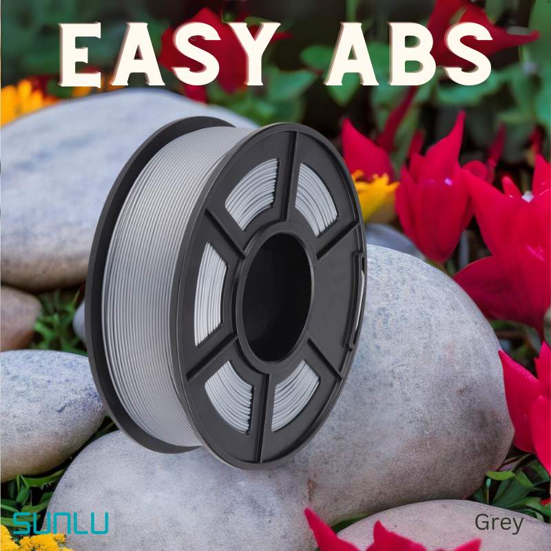 A spool of SUNLU Easy ABS 1.75mm 3D printing filament rests on rocks, with red flowers and lush greenery in the background.
