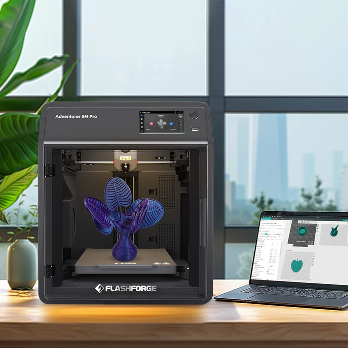 The FlashForge Adventurer 5M Pro 3D printer is quickly and easily set up, printing a purple object on a table next to a laptop with 3D modeling software; a plant and window are visible in the background.