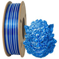 A spool of Toyar PLA Silk Rainbow Colours Alternating 1.75mm filament sits beside a detailed blue 3D-printed mask, highlighting ShenZhen Toyar Technology's exceptional 3D craftsmanship.