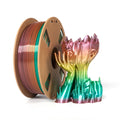 A spool of Toyar PLA Silk Rainbow 1.75mm filament sits beside a vibrant 3D-printed face and hand sculpture, both featuring matching gradient colors with the Toyar brand’s signature silk rainbow finish.