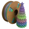A spool of Toyar PLA Matte Rainbow 1.75mm Filament is displayed beside a vibrant, multicolored 3D printed Christmas tree with a star, highlighting the bold hues and smooth matte finish possible with Toyar’s filament.