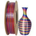 A spool of Toyar PLA Silk Rainbow Colours Alternating 1.75mm filament sits beside a 3D-printed vase, its vibrant horizontal stripes highlighting the stunning potential of Toyar creations.