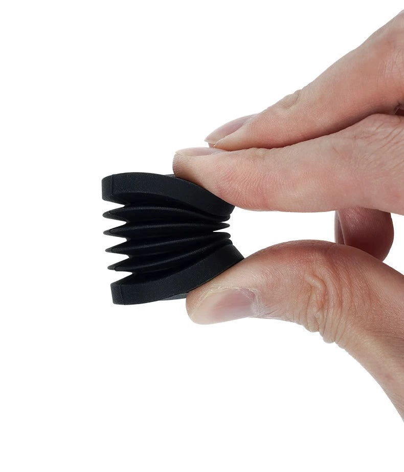 A hand holds a compact, black, accordion-shaped rubber object on a white backdrop. This Bambu Lab X1/P1P Anti-Vibration Printer Foot Pad improves 3D printer stability for smoother and quieter operation.