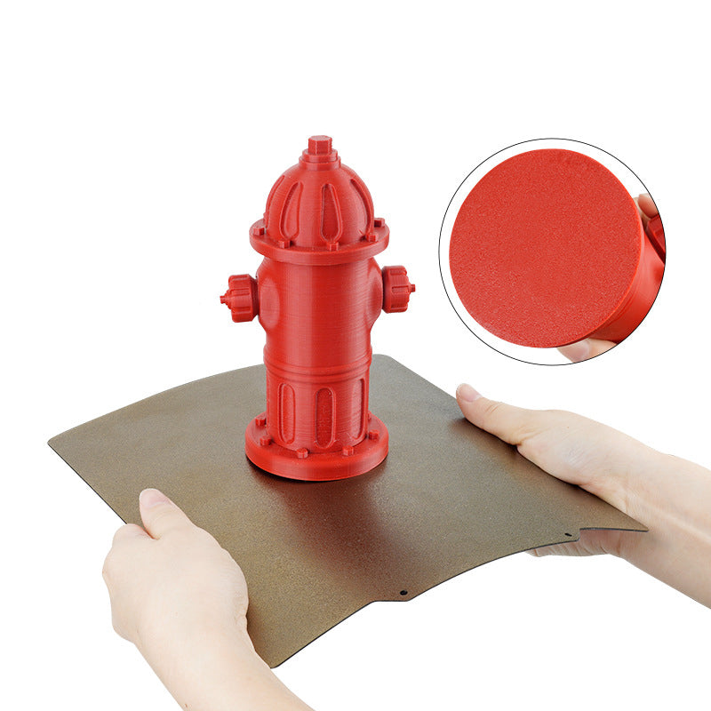 Hands holding a Double Side Coated PEI Hot Bed Platform with Magnetic Base from Cirrus Link - 3D Printing Online Store, showcasing a red fire hydrant model. A zoomed-in circle highlights the print texture, illustrating its high-temperature resistance.
