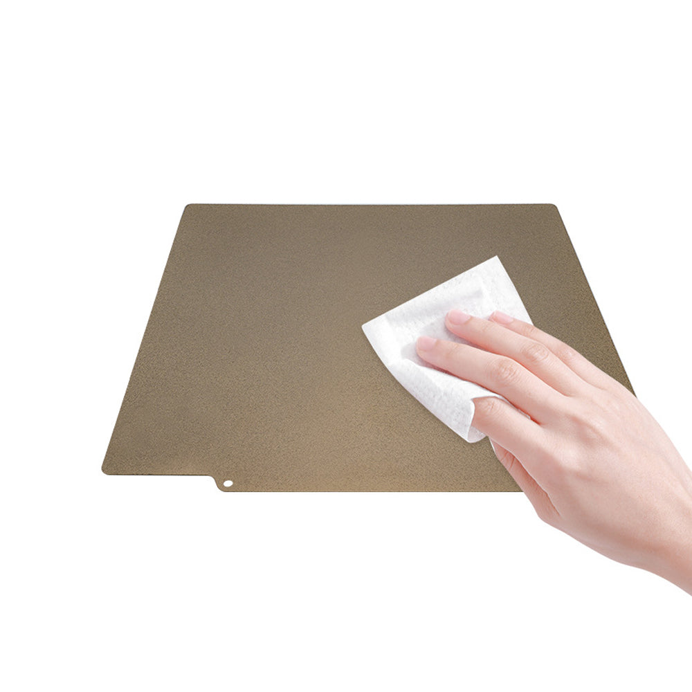 A hand wipes a Cirrus Link Double Side Coated PEI Hot Bed Platform with a cloth on a white background, ensuring its pristine condition and maintaining its high-temperature resistance.
