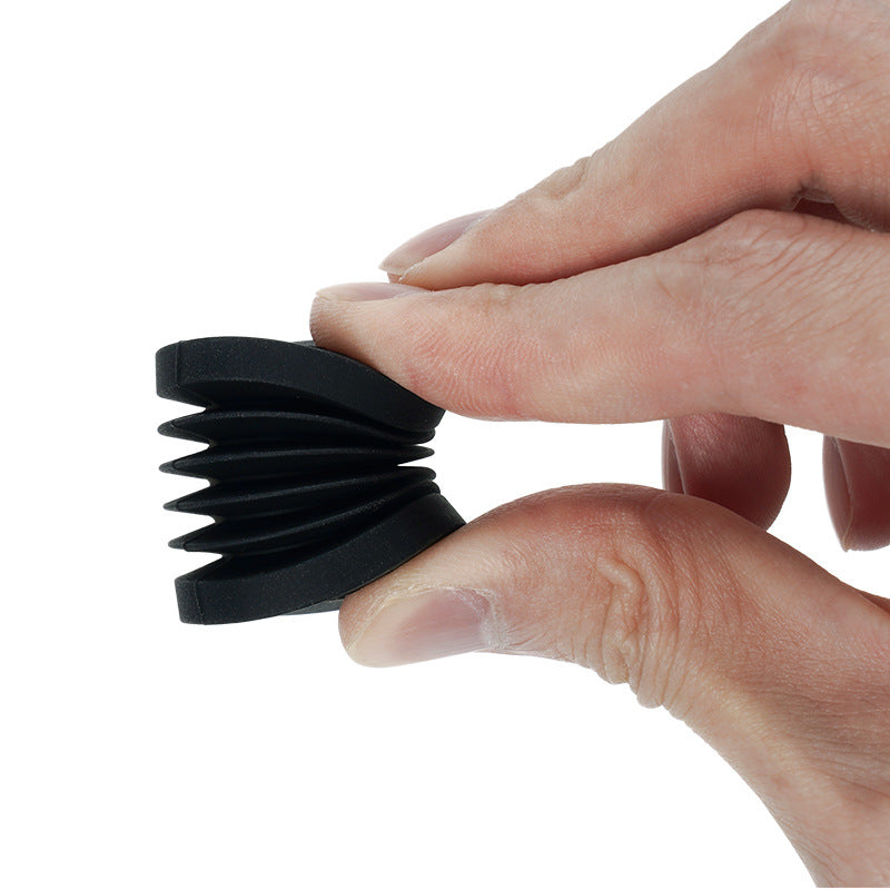 A hand squeezing a small, black, accordion-like rubber object between thumb and index finger, reminiscent of the intricate designs possible with 3D printing or the precision found in 3D Printing Perth - Cirrus Link's Bambu Lab X1C P1P Extruder V2.0 with Hardened Steel Hot End Upgrade and Fixing Bracket.