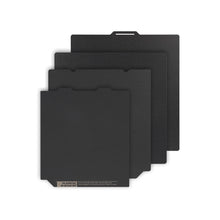 Four black swatches of the Polyurea Hot Bed Platform, each differing in size, are stacked and fanned out against a white background, showcasing the precision associated with 3D Printing Perth - Cirrus Link's products for materials like PLA, PETG, and ABS.