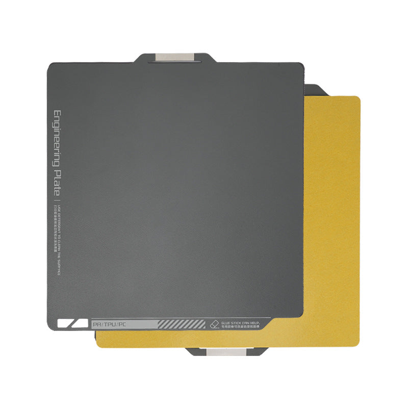 Two overlapping square engineering plates, one in sleek gray with marked text and a smooth finish, and the other with a gold finish. This design is reminiscent of the precision found in 3D Printing Perth's Bambu Lab X1 Magnetic Steel 268*258mm Print Surface.