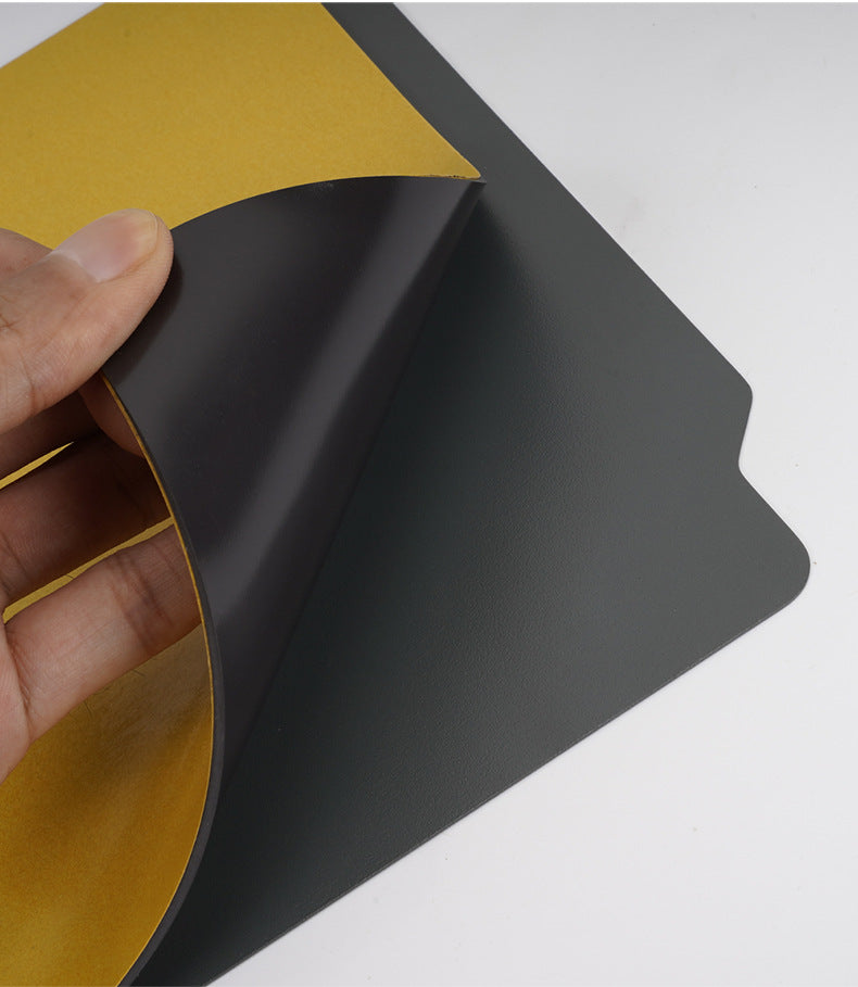 A hand holds a sheet of yellow adhesive vinyl, partially peeled back to expose the black backing on the 3D Printing Perth - Cirrus Link's Bambu Lab X1 Magnetic Steel 268*258mm Print Surface.